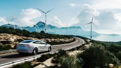 1972202852 Electric car drive on the wind turbines background.